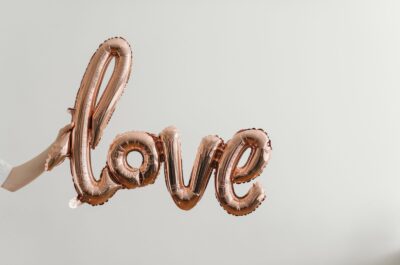 Hand holding balloon spelling love in cursive